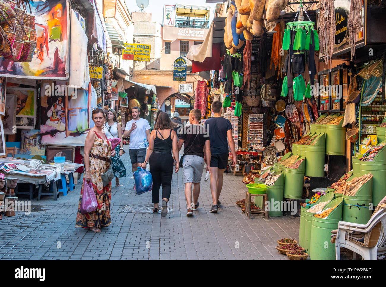 Flânez dans les acheteurs ruelle de médina de Marrakech bordée d'étals de marché de l'art, d'épices, et d'autres marchandises, Maroc Banque D'Images