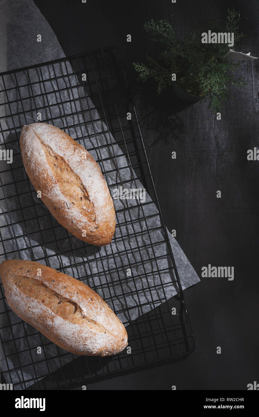 Baguette, pain de style européen sur la table en bois noir en matin temps avec effet de lumière difficile. Repas biologiques et sains dans un style minimaliste concept Banque D'Images