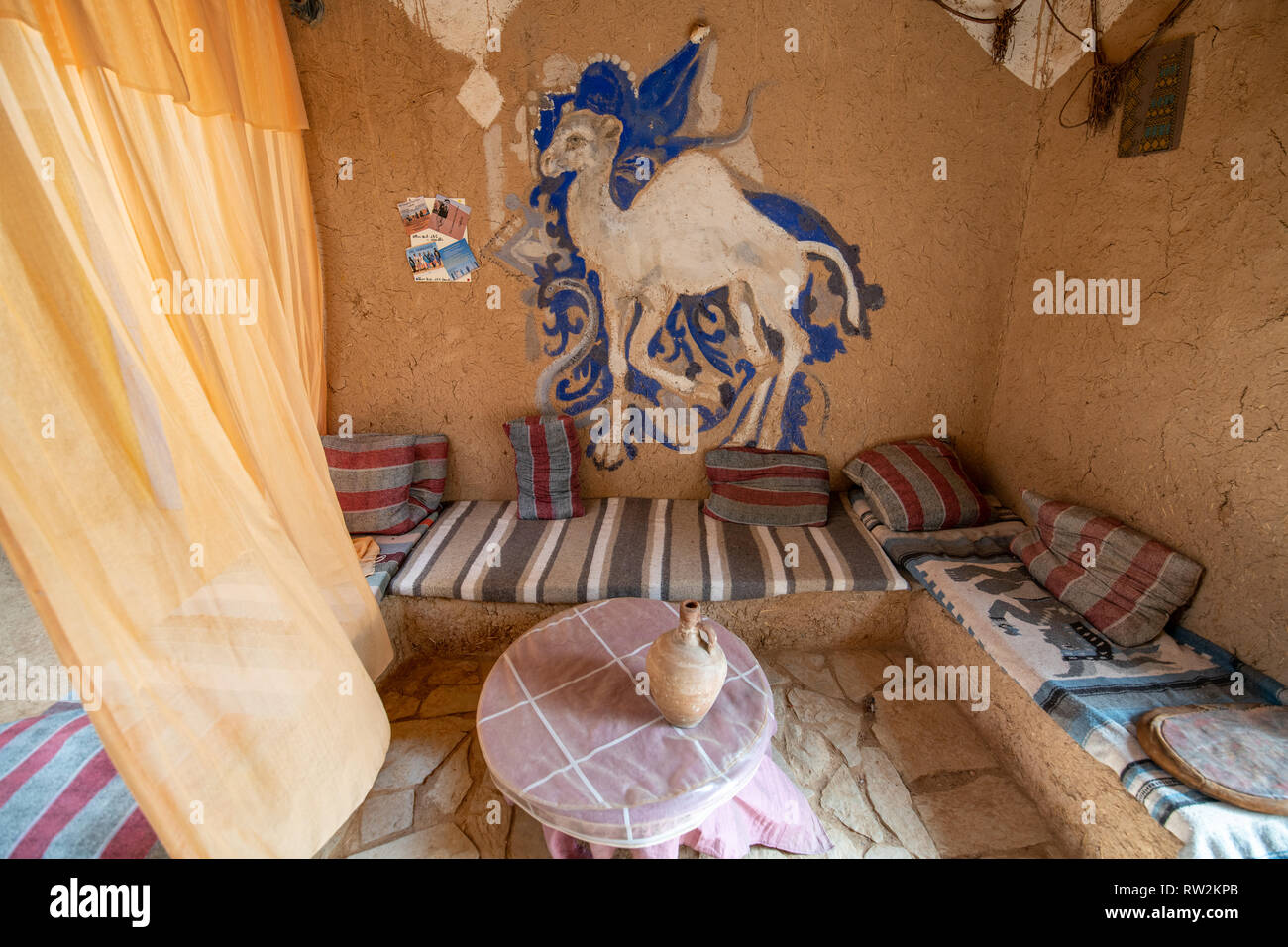 L'espace salon intérieur avec l'inscription chameau dessiné sur le mur de boue-brique traditionnel construit maison, oasis Tighmert, Maroc Banque D'Images