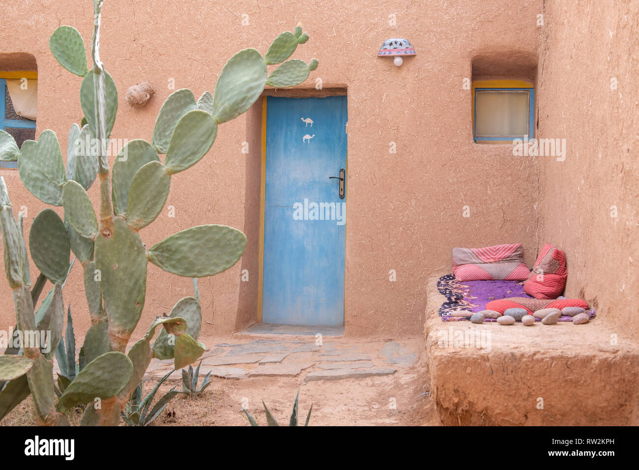 Extérieur de maison construite en pisé avec porte bleue et cactus en avant, Oasis Tighmert, Maroc Banque D'Images