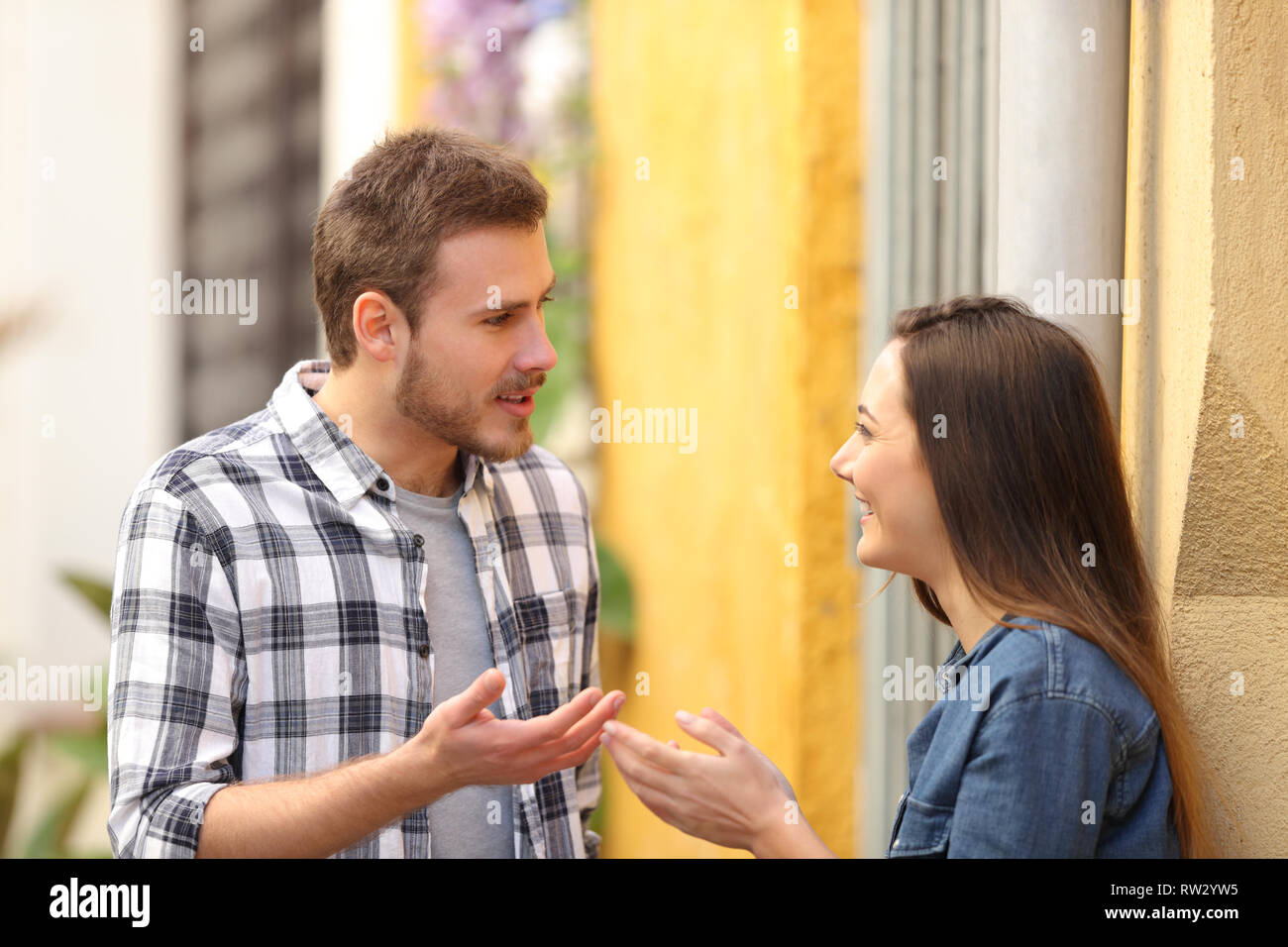 Couple heureux de parler debout dans une rue colorée Banque D'Images