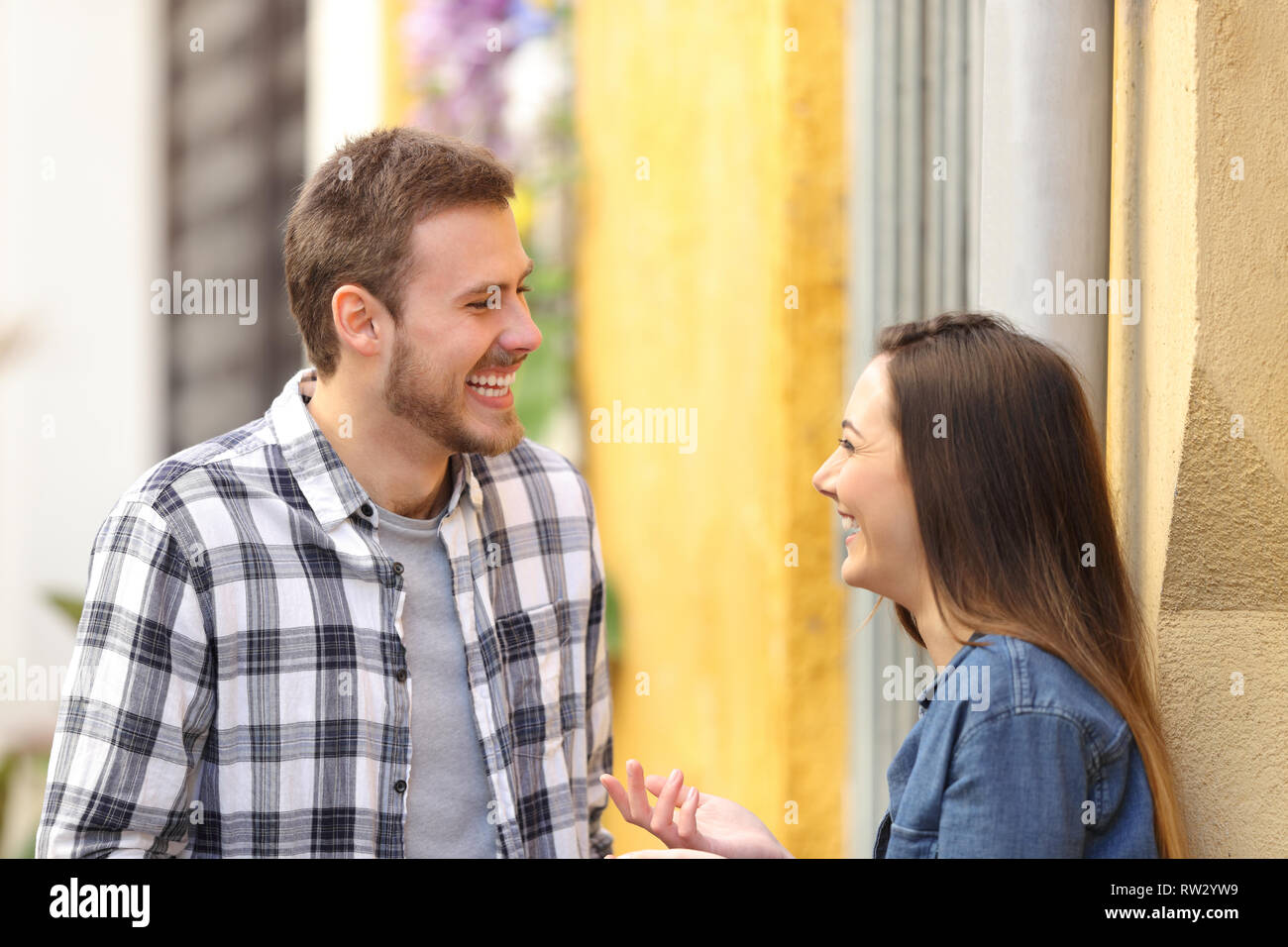 Heureux couple parler et rire debout dans une rue colorée Banque D'Images