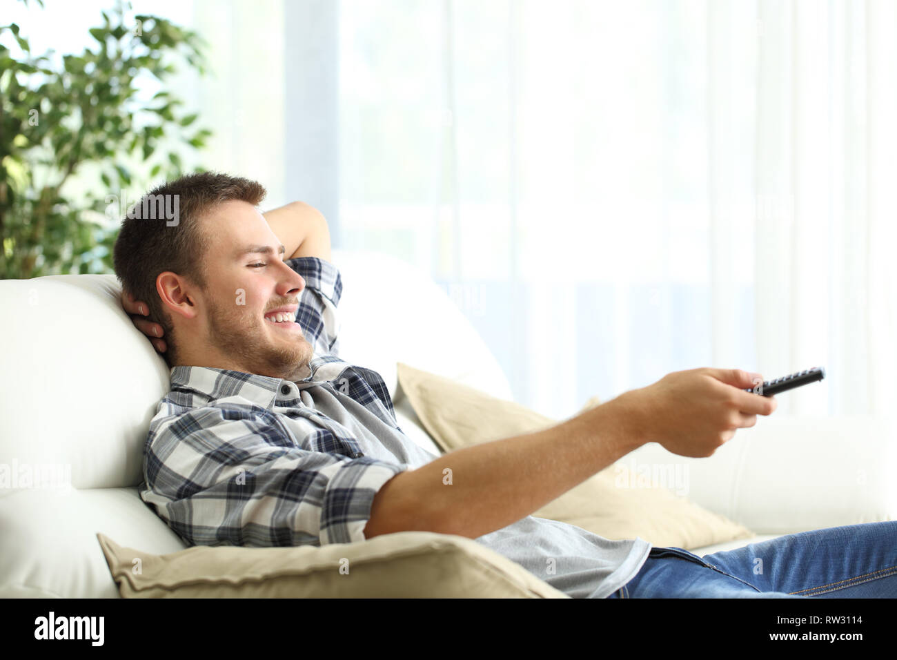 Vue de côté portrait d'un homme heureux se détendre en regardant la télé assis sur un canapé dans la salle de séjour à la maison Banque D'Images