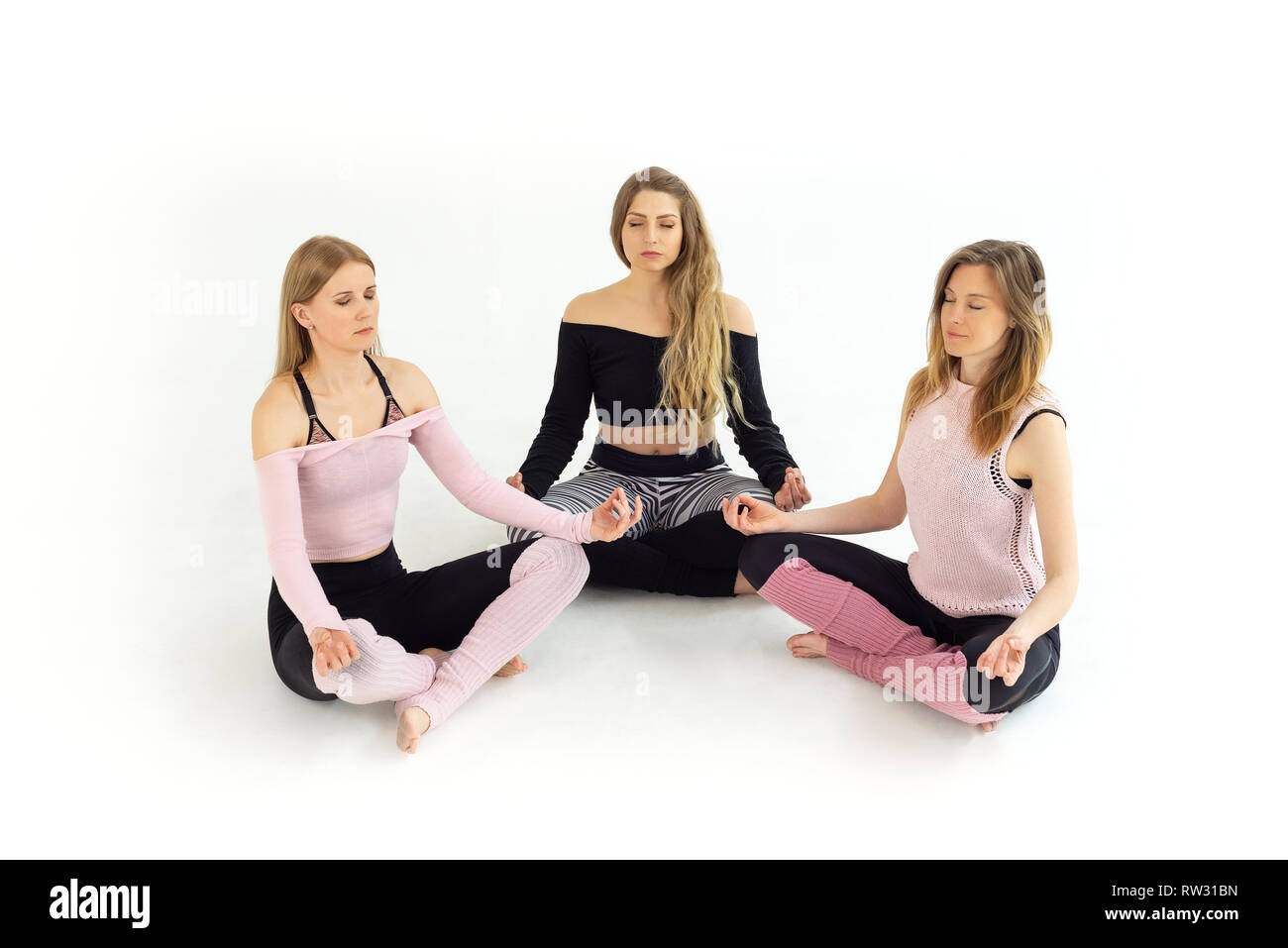 Groupe de jeunes belles filles de trois personnes faisant du yoga, la méditation zen avec les yeux fermés. Fond blanc Banque D'Images