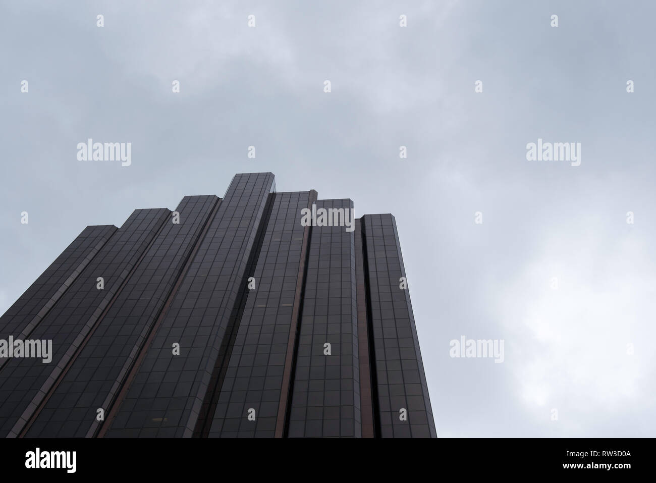 Une tour de bureaux en hauteur anonyme, générique et à façade de verre sombre avec ciel nuageux gris couvert à Sydney, en Australie Banque D'Images