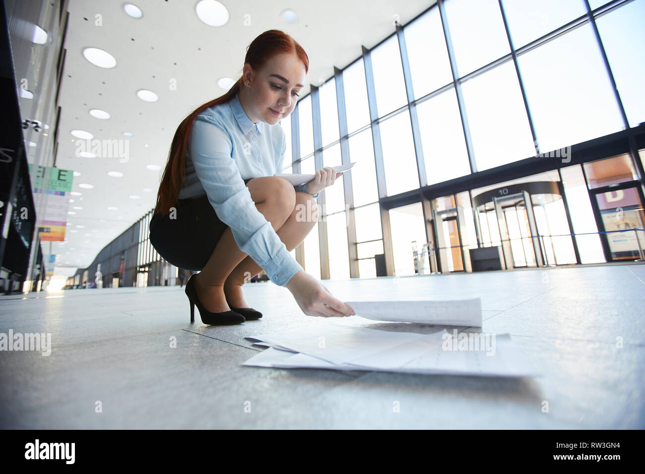 Portrait of young businesswoman ramasser des papiers de bureau en étage hall, copy space Banque D'Images