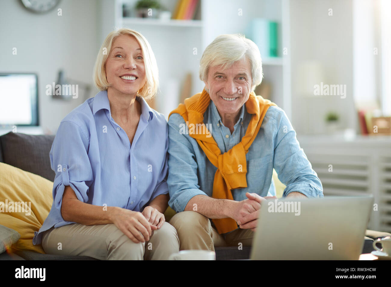 Contemporain Portrait de senior couple sitting on sofa at home and looking at camera, copy space Banque D'Images