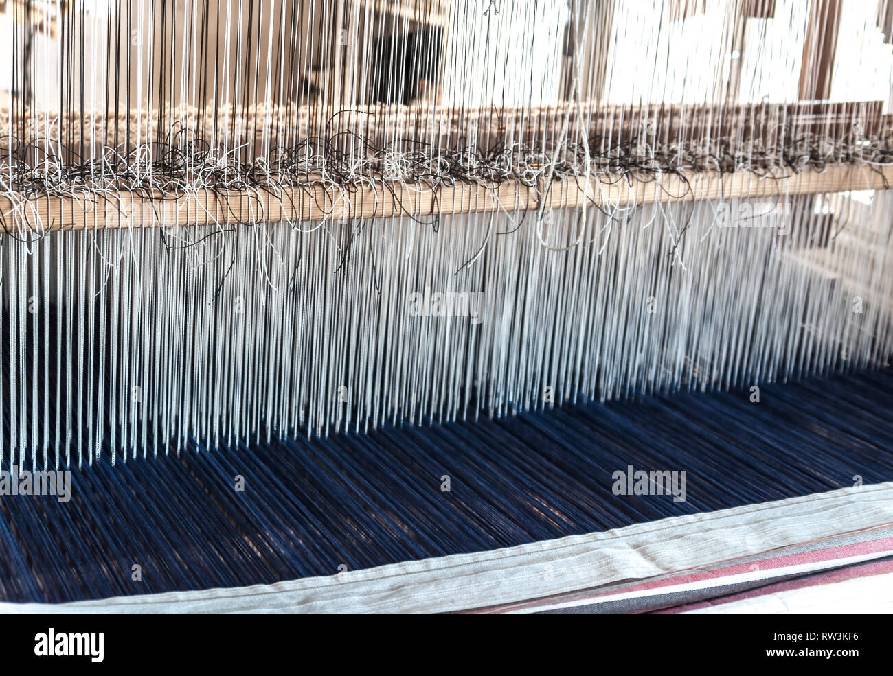 Détail d'un ancien métier à tisser traditionnel vintage avec de nombreuses cordes de coton liée à un cadre en bois comme un outil de fabrication pour travaux manuels professionnels Banque D'Images