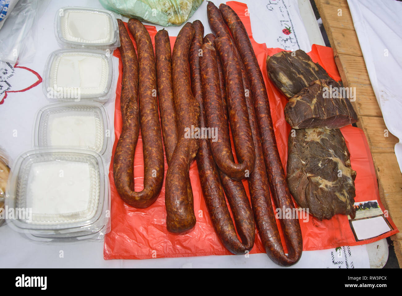 Des saucisses fumées et séchées et autres produits se distinguent sur la table pour la vente. Banque D'Images Des saucisses fumées et séchées et autres produits se distinguent sur la table pour la vente. Banque D'Images