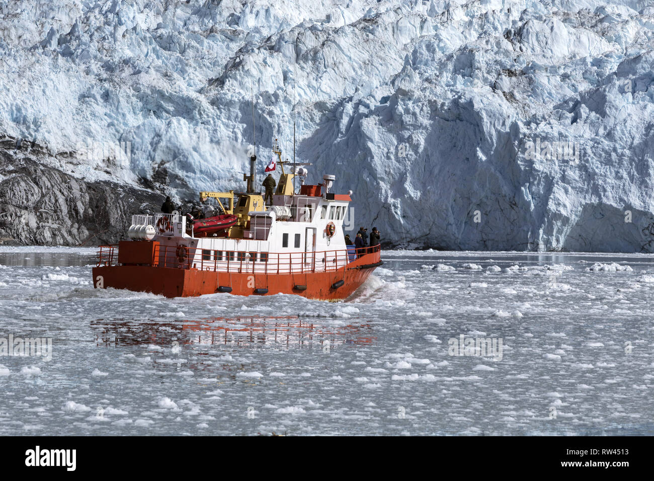 Bateau de croisière rouge parmi les icebergs au Groenland. Nautisme en face de glacier Eqip Sermia dans la mer gelée Banque D'Images