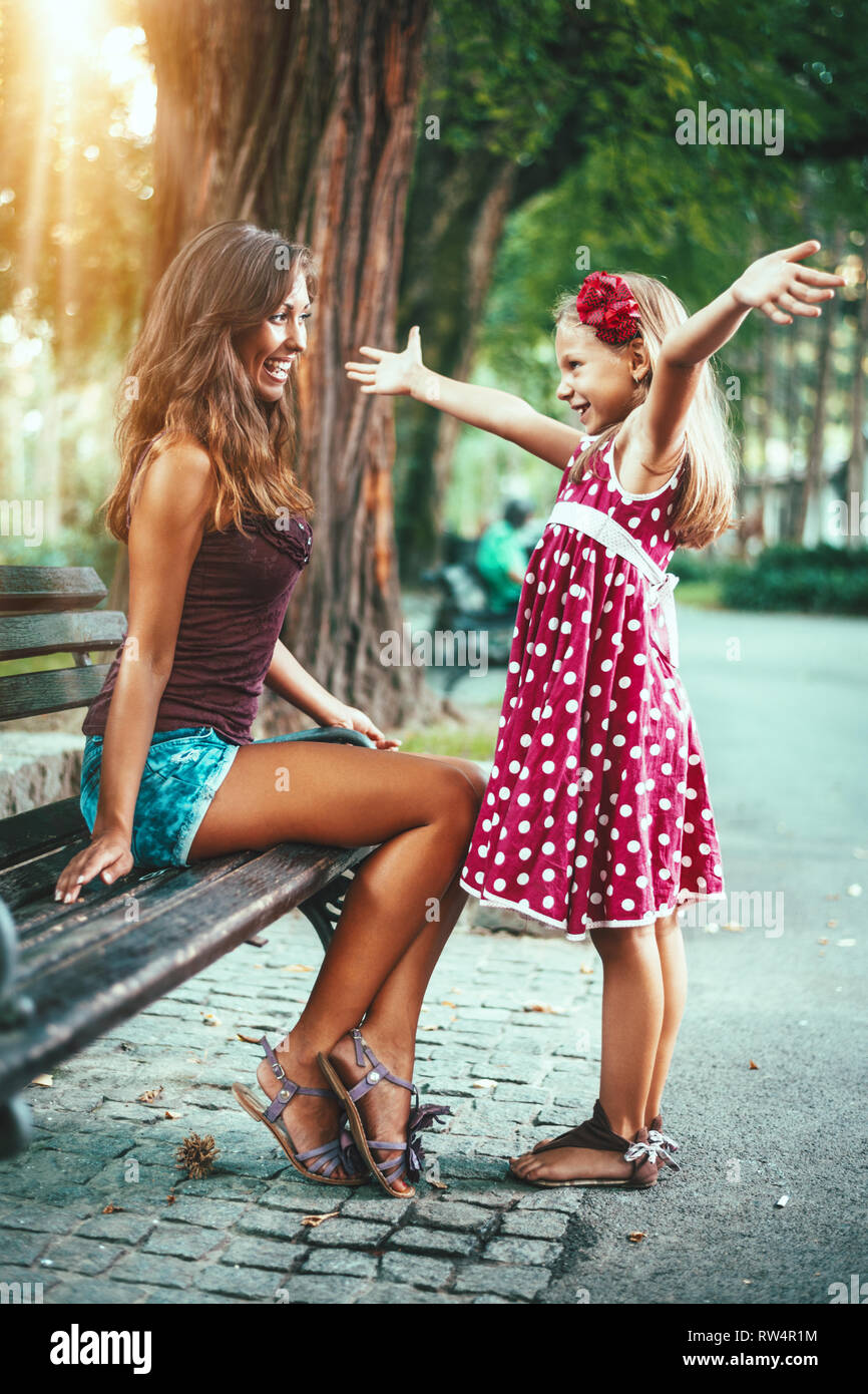 Belle Mère et fille s'amusent au parc au printemps. Petite fille soulève ses mains pour enlacer sa mère. Banque D'Images