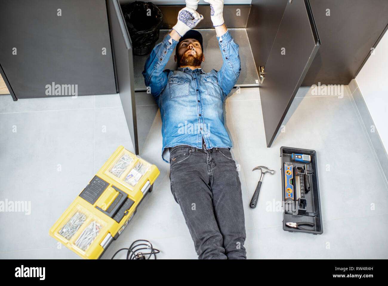 Réparer la plomberie cuisine homme couché sous le lavabo à l'étage, vue d'en haut Banque D'Images