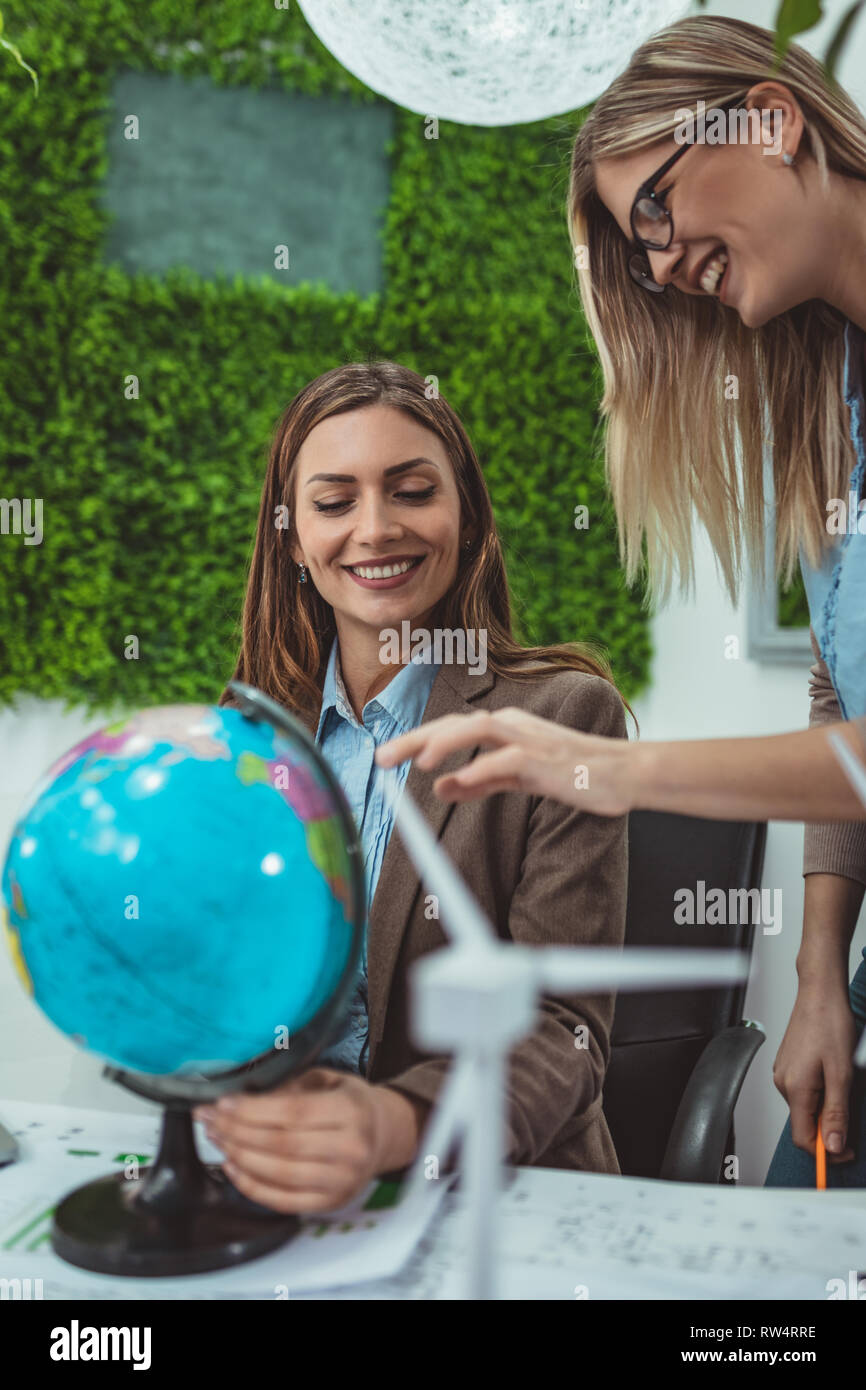 Les jeunes femmes d'une stratégie réussie en réunion à l'office sont à discuter de nouveaux marchés à la recherche à un globe. Banque D'Images