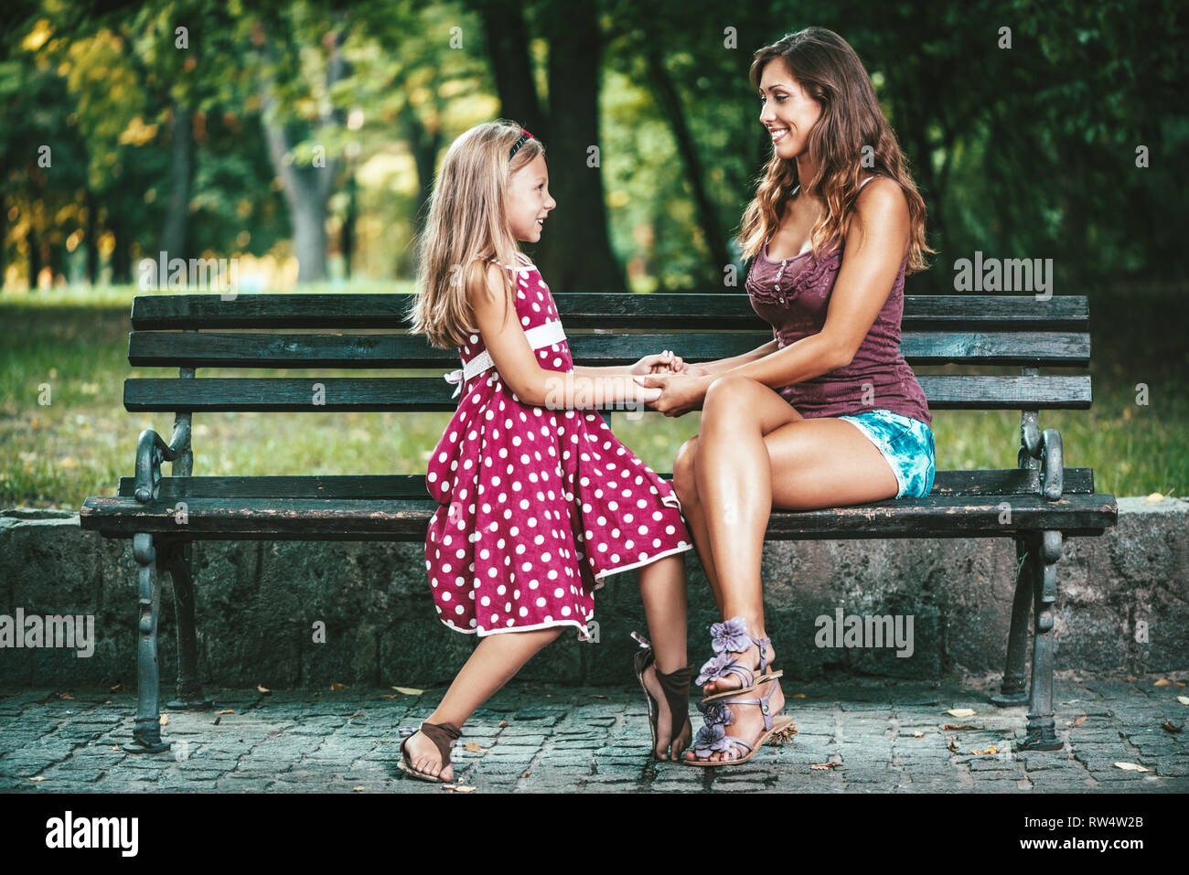 Belle Mère et fille s'amusent au parc au printemps, se tenant la main les uns les autres. Banque D'Images