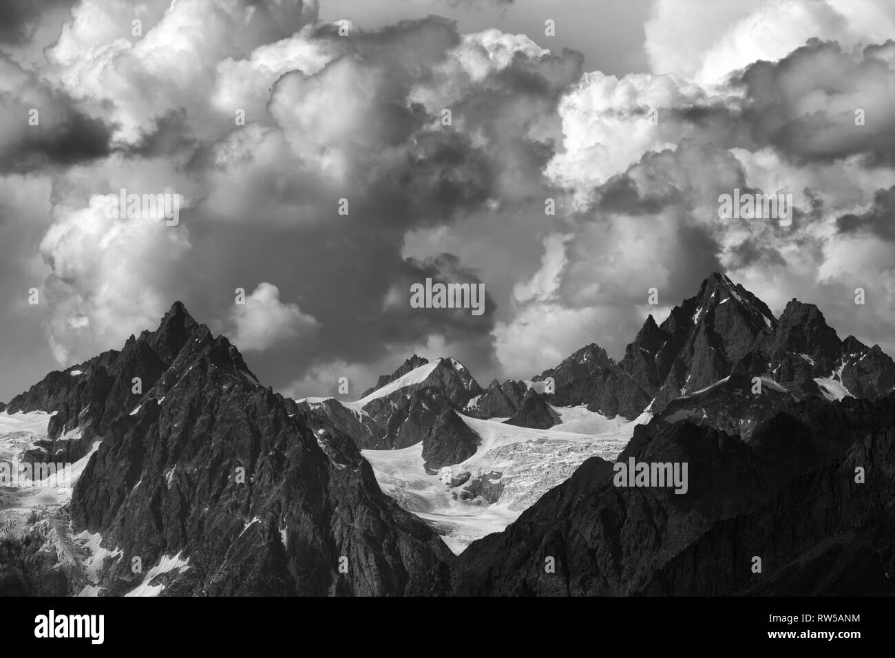 De hautes montagnes avec des glaciers et le ciel nuageux au jour d'été. Montagnes du Caucase, la Géorgie, la région Svaneti. Paysage aux tons noir et blanc. Banque D'Images