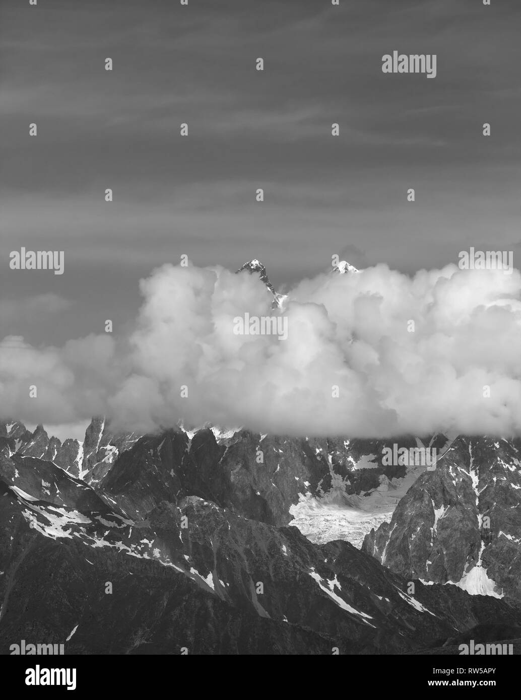 De hautes montagnes avec de la neige dans les nuages à jour d'été. Montagnes du Caucase, la Géorgie, la région, le Mont Ushba Svaneti. Paysage aux tons noir et blanc. Banque D'Images