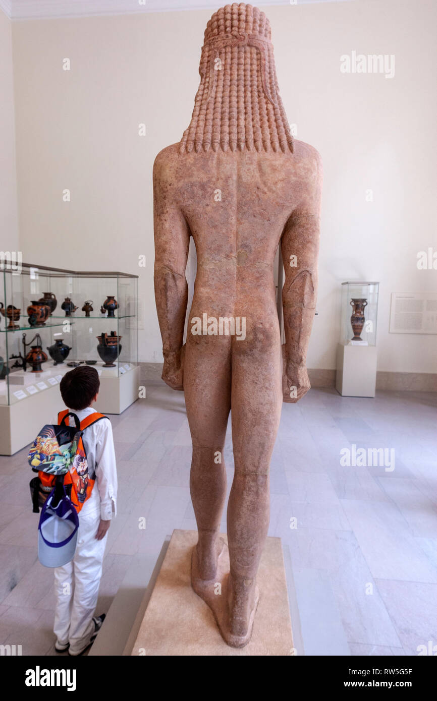 Garçon posant près de la statue en marbre d'un kouros (jeunesse), l'art égyptien, le Metropolitan Museum of Art, Manhattan, New York USA Banque D'Images