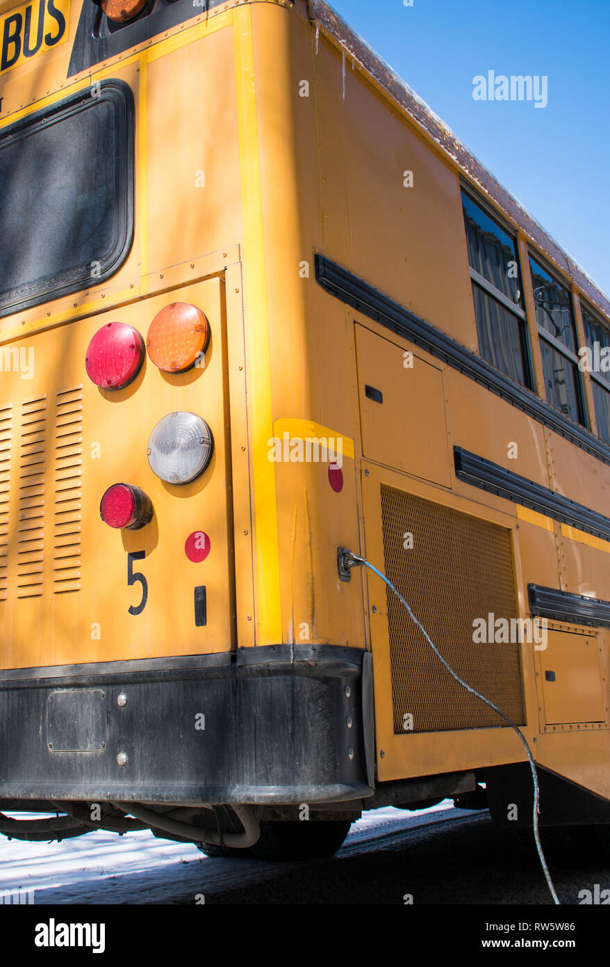 Low angle view of a US school bus en hiver avec chauffe-moteur branché Banque D'Images