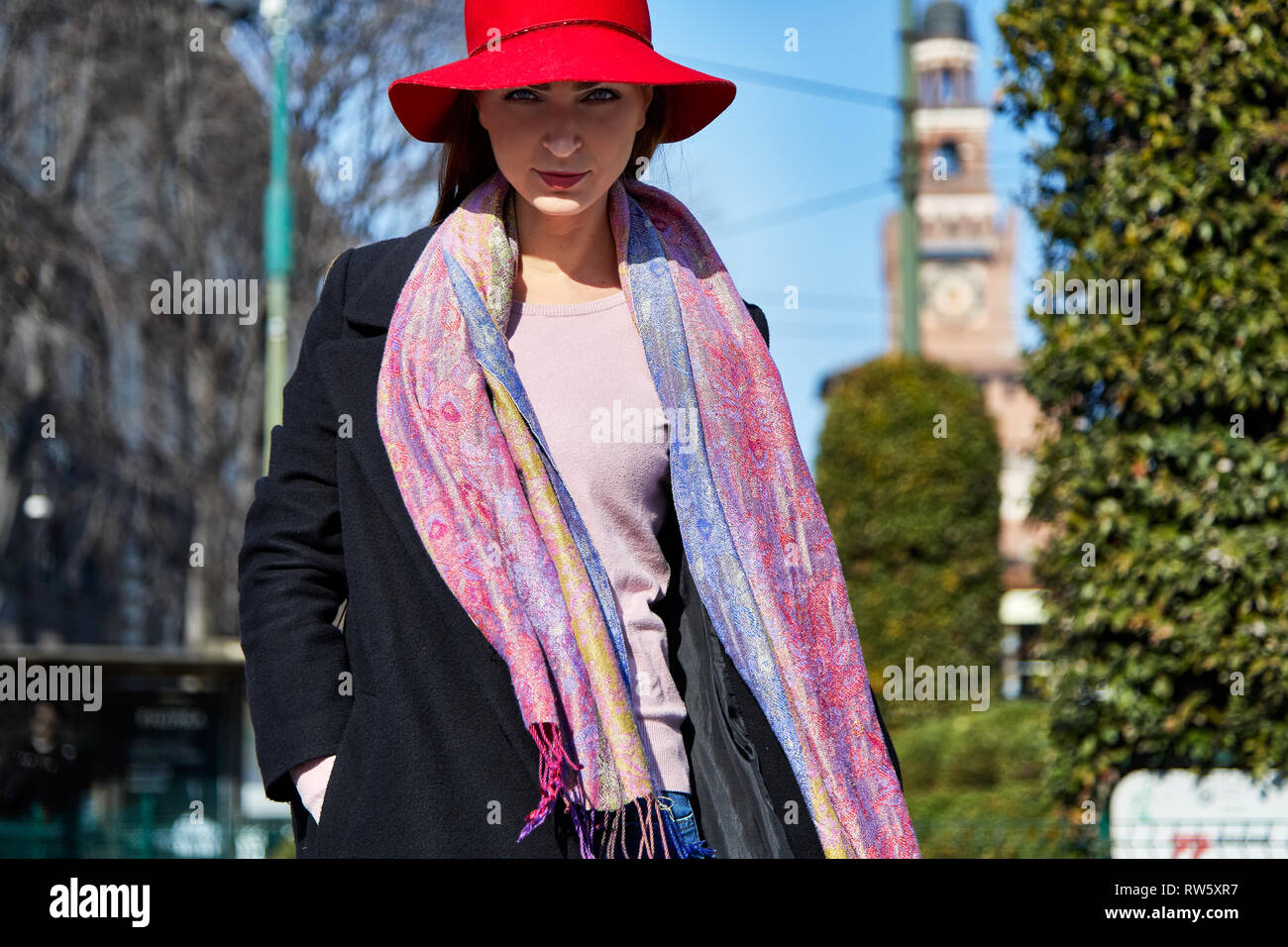 Mannequin posent avec une écharpe rouge har, et manteau noir pour un portrait avec Castelo Sforzesco de Milan à l'arrière-plan dans une journée ensoleillée Banque D'Images