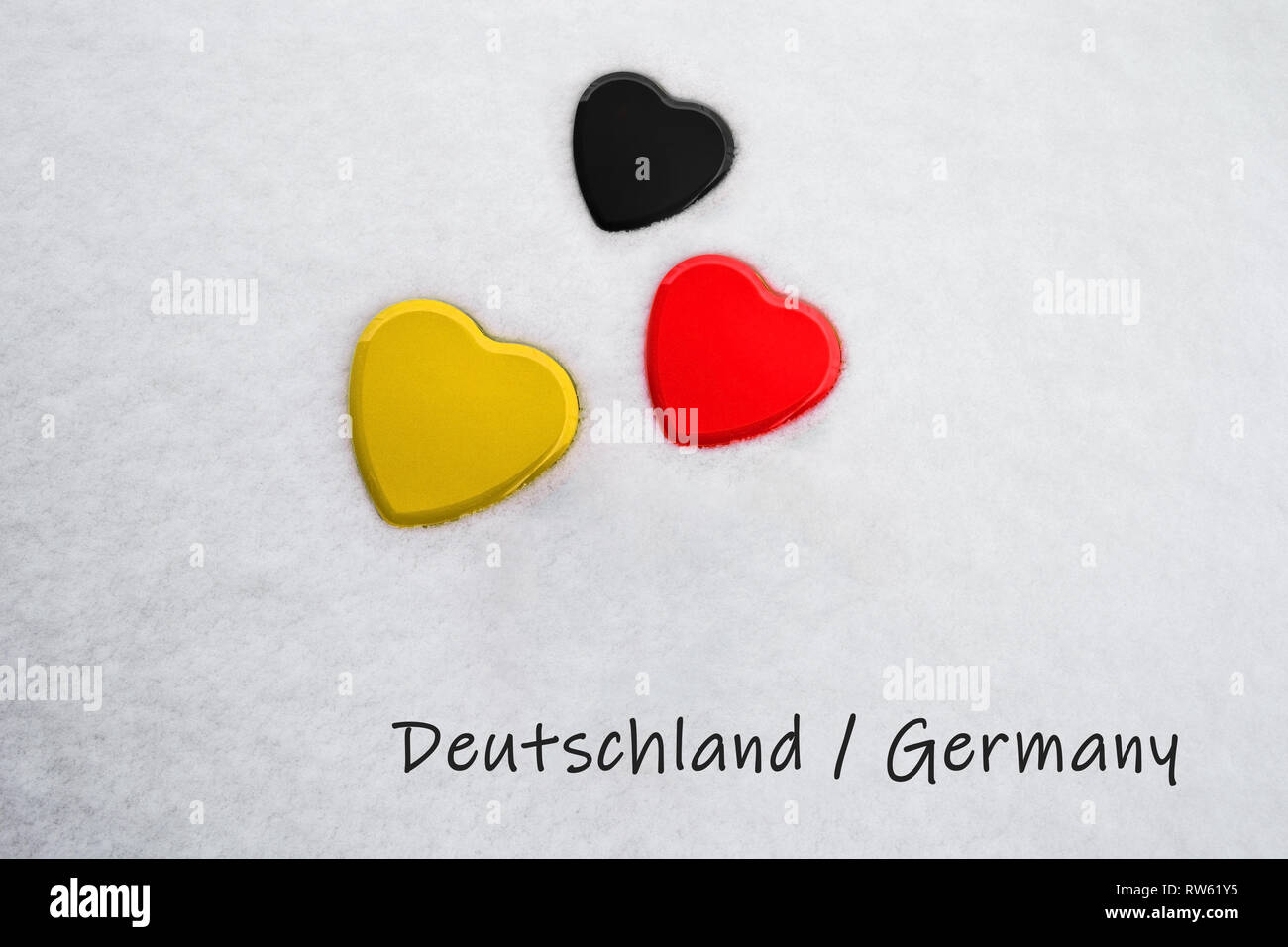 Couleurs du drapeau allemand (noir, rouge, jaune) Mandarine peint sur trois cœurs. La neige fond avec le pays, l'Allemagne, écrit Banque D'Images