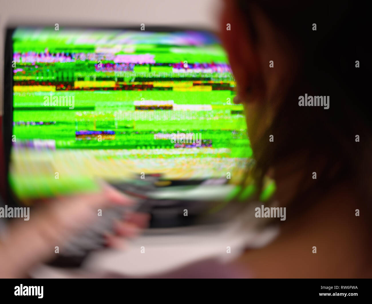 Vue arrière du woman holding remote control à mauvais signal à bruit statique de son écran de télévision TVN numérique effet swirl Banque D'Images