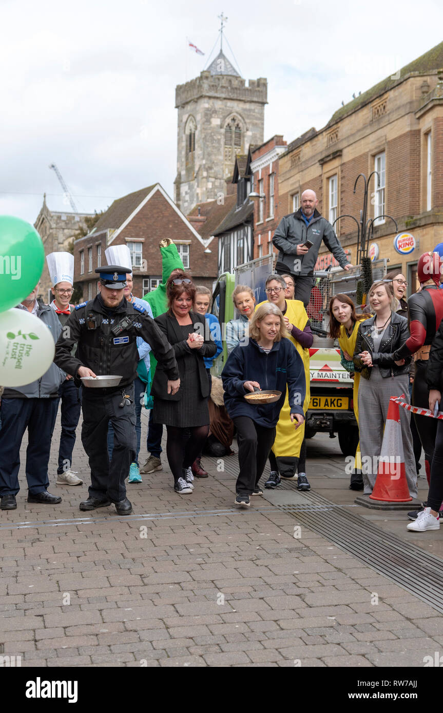 Salisbury, Wiltshire, Royaume-Uni. 5e Mar, 2019. Les concurrents en compétition dans la course aux crêpes sur High Street, Salisbury. L'événement est organisé par l'église Saint-Thomas et l'Trussell Trust. Banque D'Images