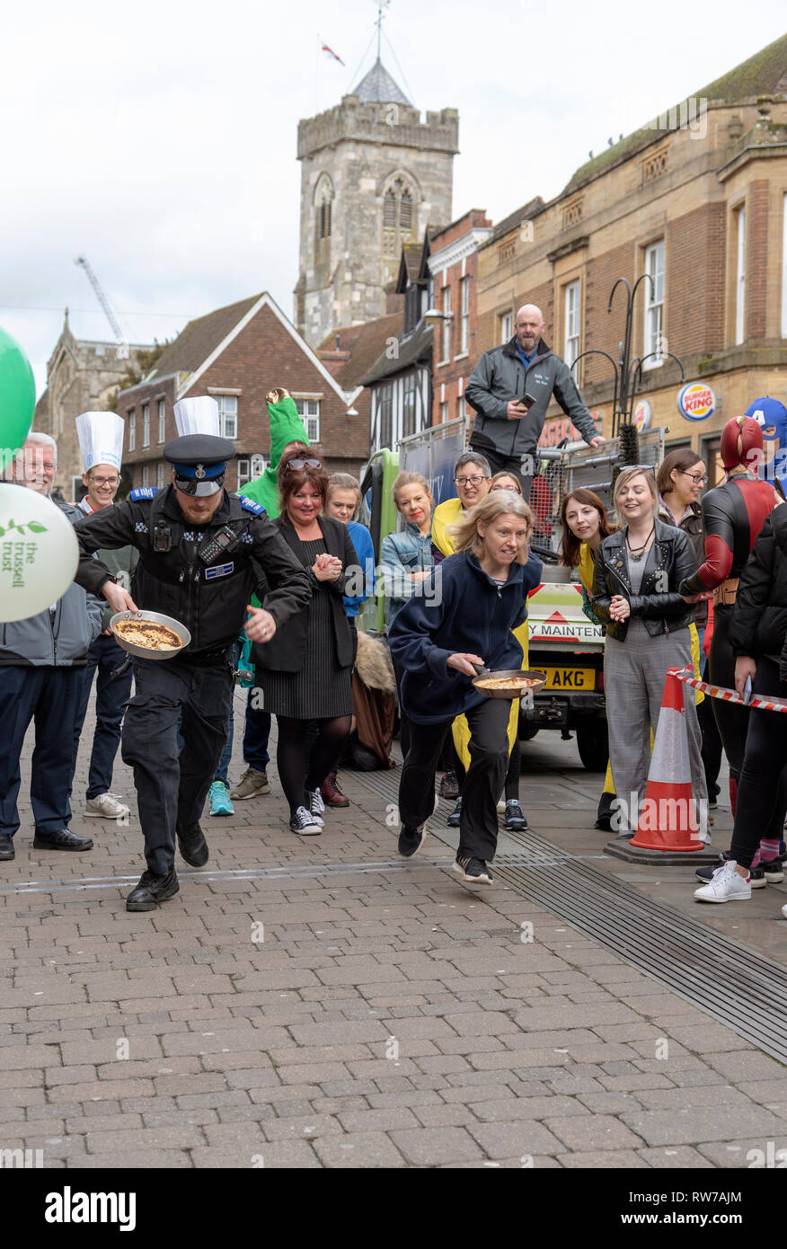 Salisbury, Wiltshire, Royaume-Uni. 5e Mar, 2019. Les concurrents en compétition dans la course aux crêpes sur High Street, Salisbury. L'événement est organisé par l'église Saint-Thomas et l'Trussell Trust. Banque D'Images