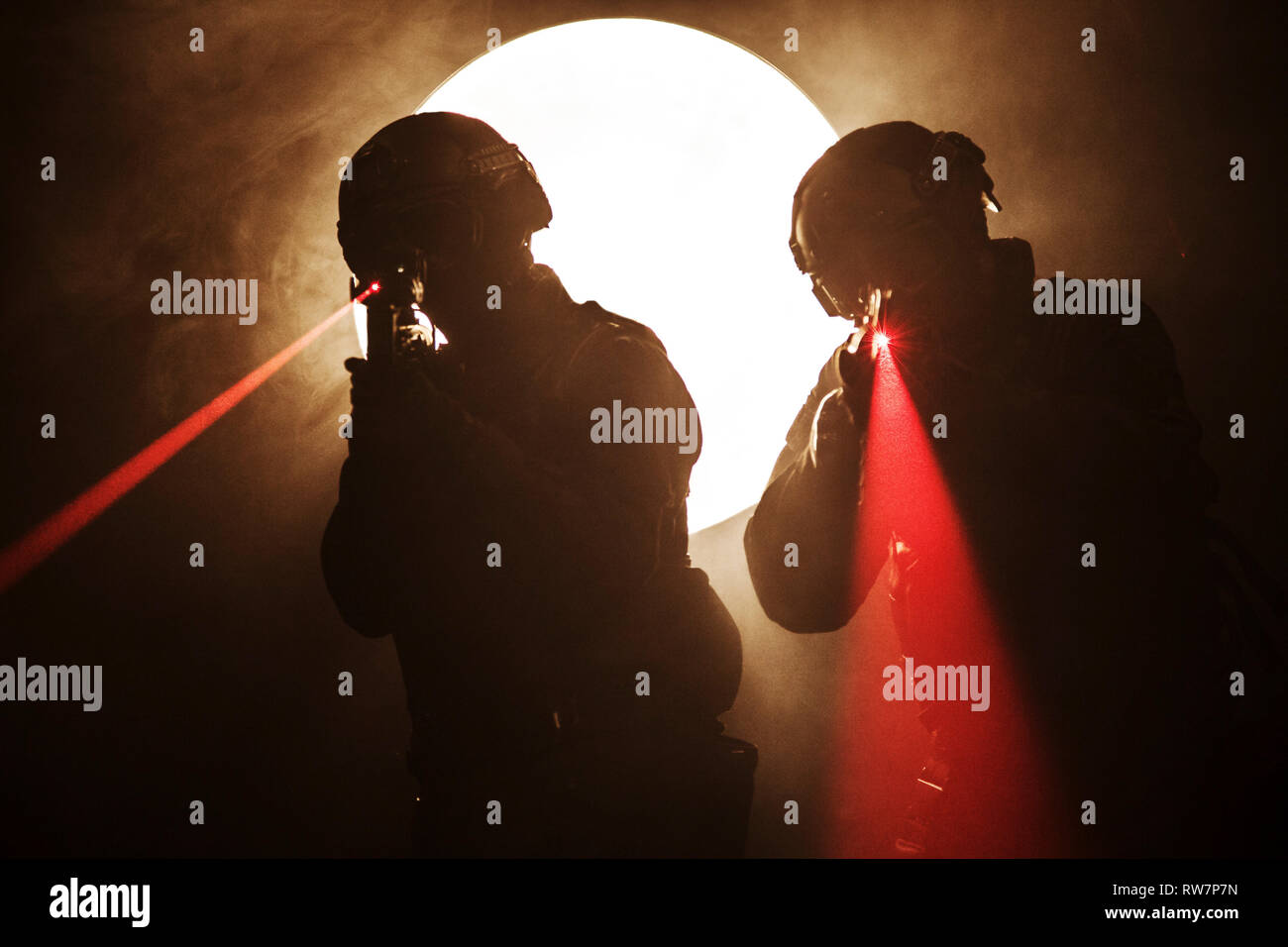 Spec Ops policiers SWAT dans la fumée et le feu avec le laser sites touristiques. Banque D'Images