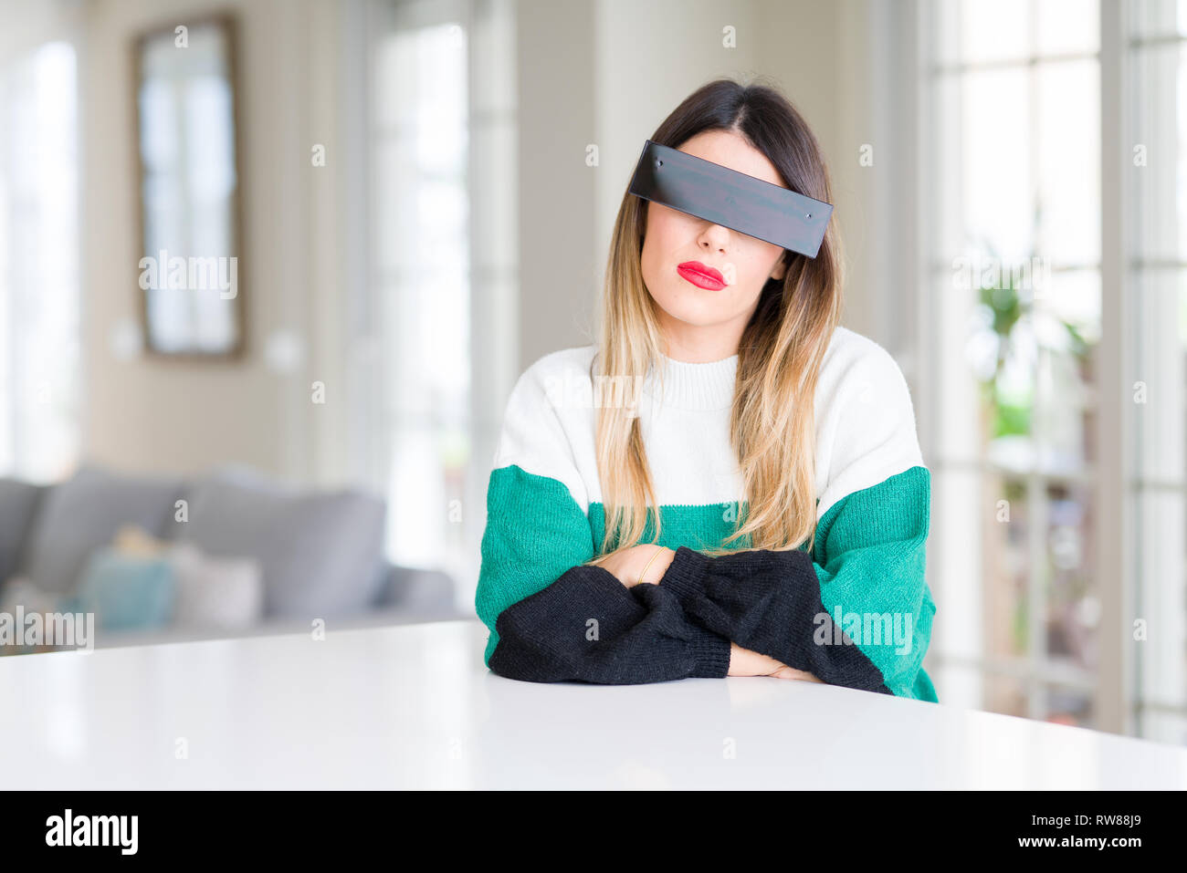 Belle jeune femme bandeau yeux noir avec bande de censure à la maison  sceptique et nerveux, désapprouvant expression sur le visage avec les bras  croisés. P négative Photo Stock - Alamy