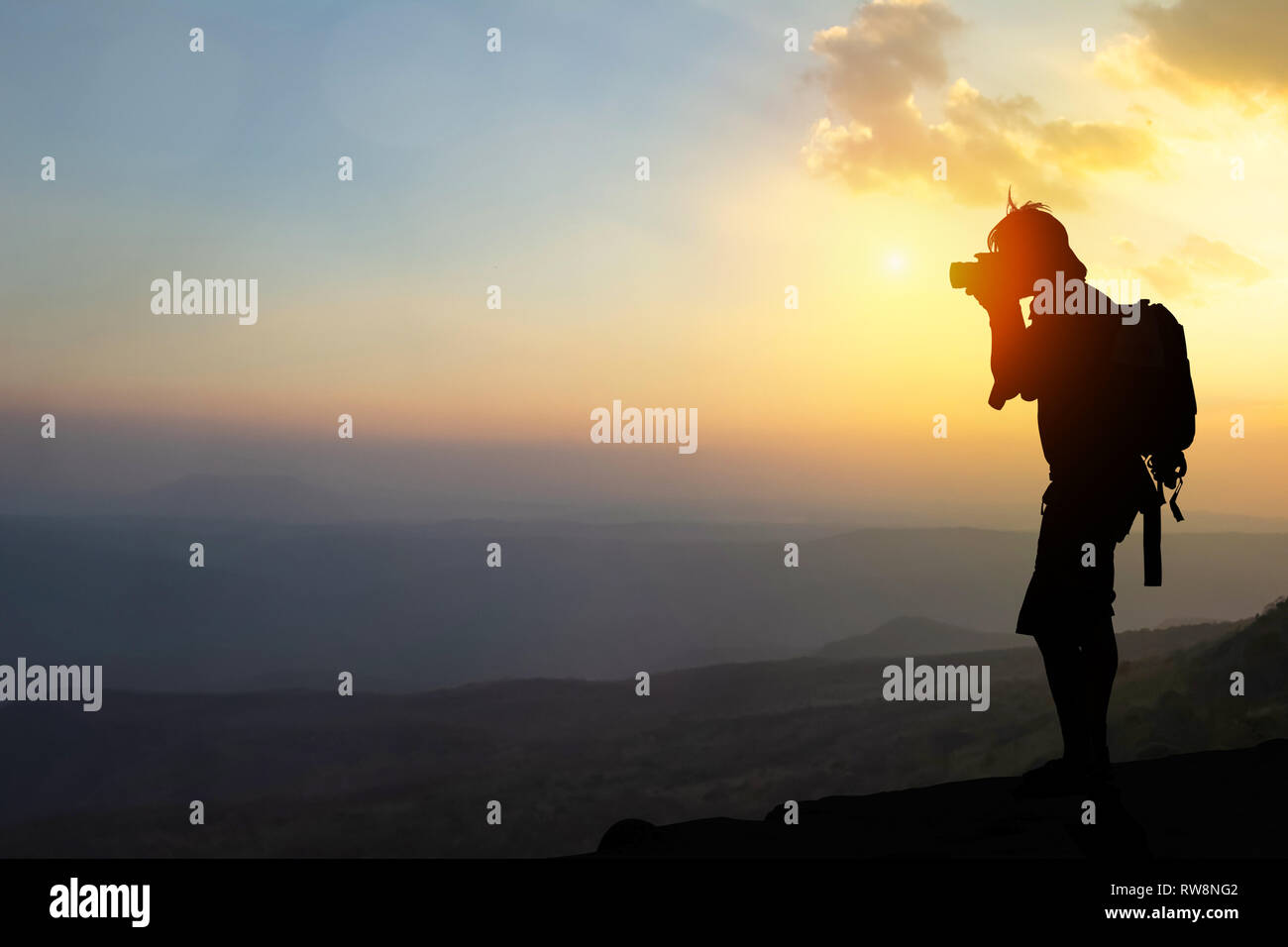 De style vintage trouble résumé comme la lumière orange de l'automne. Le jeune photographe sur les montagnes et les arbres, regardant le paysage pendant le lever du soleil d'or Banque D'Images