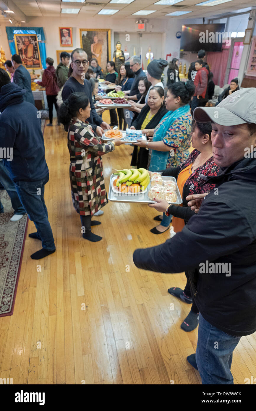 Fidèles à un temple bouddhiste forment une chaîne de montage d'offrir des aliments préparés et cuisinés pour leurs moines. Dans Elmhurst, Queens, New York Banque D'Images