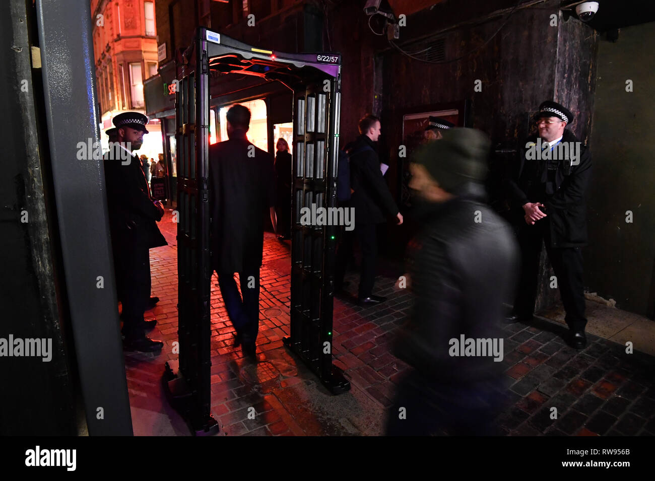 Un homme passe par un passage de couteau qui a été mis en place par les agents de la police métropolitaine de Walker's Court, entre Piccadilly Circus et les stations de métro d'Oxford Circus à Londres. Banque D'Images