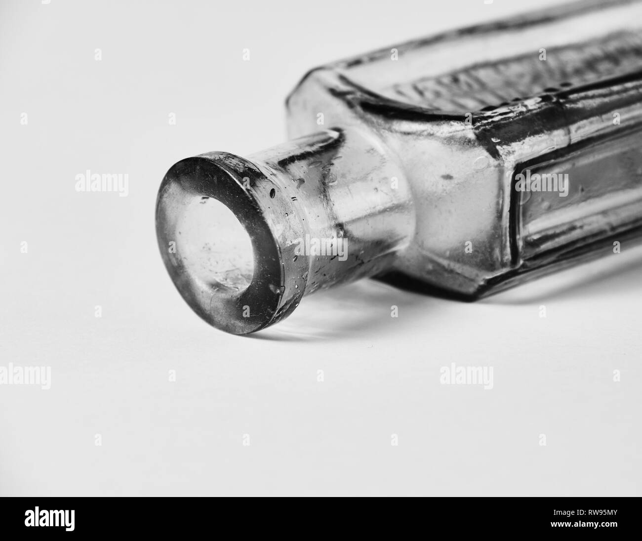 Une bouteille vide sur le côté en noir et blanc avec un fond blanc lumineux. Banque D'Images