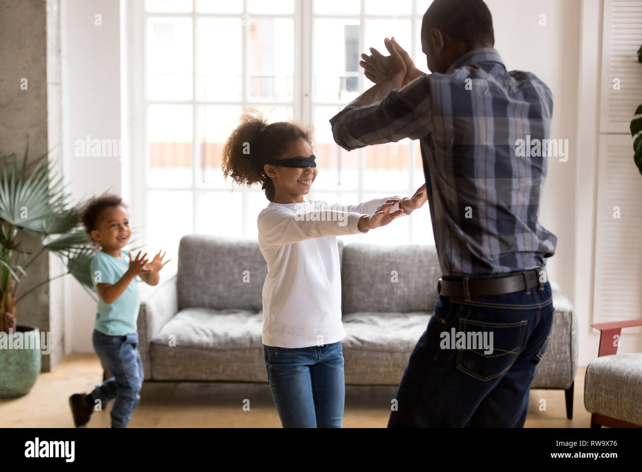 Petite fille aux yeux bandés joue à cache-cache avec la famille Banque D'Images