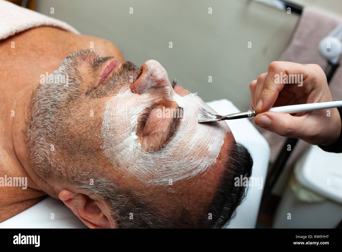 Homme d'âge moyen dans un salon de beauté avec un masque facial. Banque D'Images