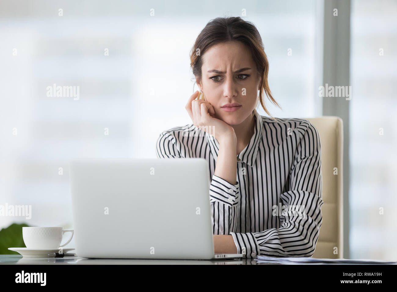 Confus businesswoman agacé par problème en ligne looking at laptop Banque D'Images