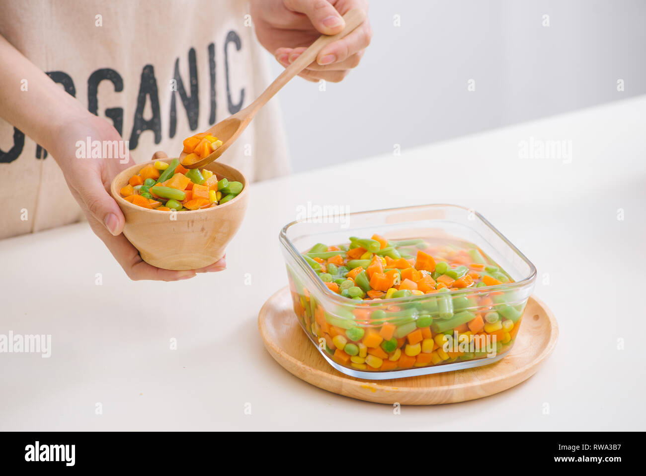 Louche de jeunes légumes fraîchement récoltés à la vapeur y compris les carottes, en Coupe ondulée, de pois et de pommes de terre pour un accompagnement sain pour le dîner Banque D'Images