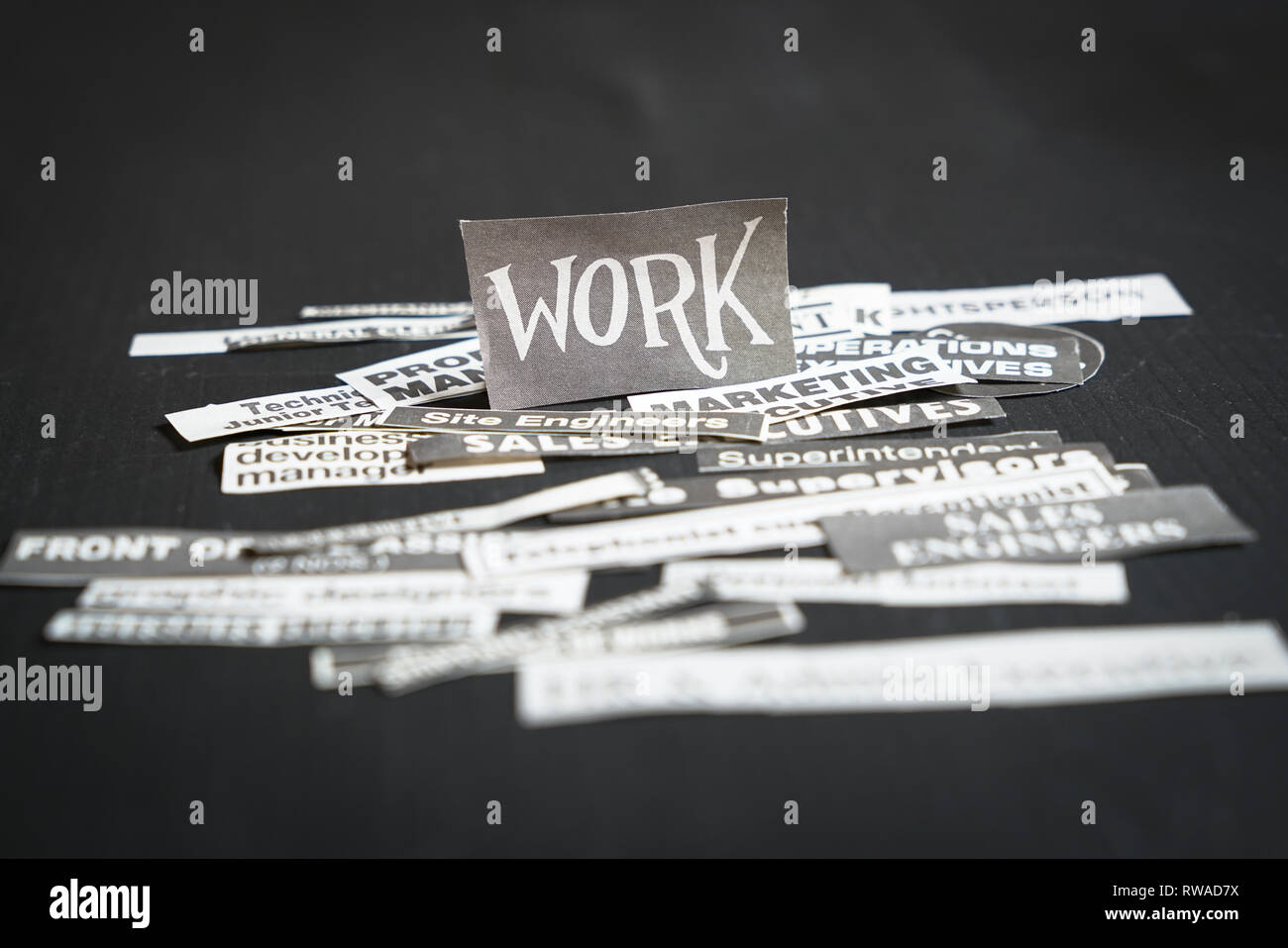 Emplois ou carrières concept : plusieurs titres d'emplois ou professions coupé de journal avec des travaux sur la pile et sur fond noir Banque D'Images