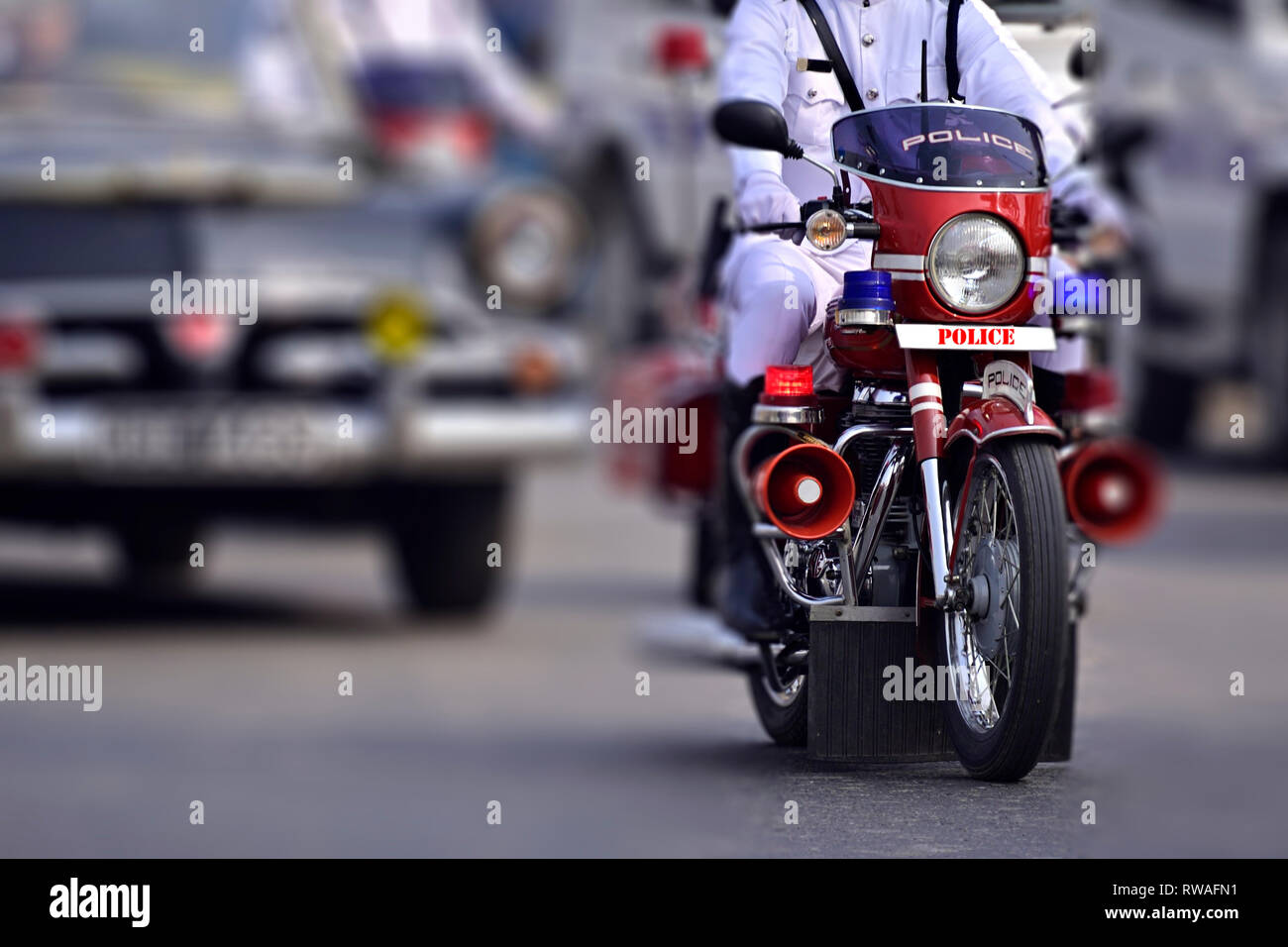 La police se déplace en moto dans la rue. Le texte « police » en rouge devant la moto contre le blanc est écrit à l'aide d'un logiciel de traitement de photos. Banque D'Images