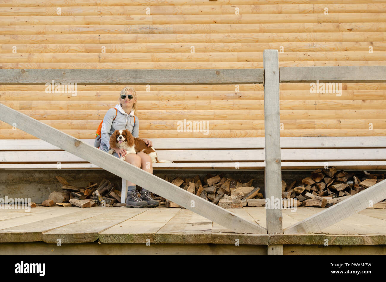 Femme assise sur un banc en bois avec son chien sur ses genoux Banque D'Images