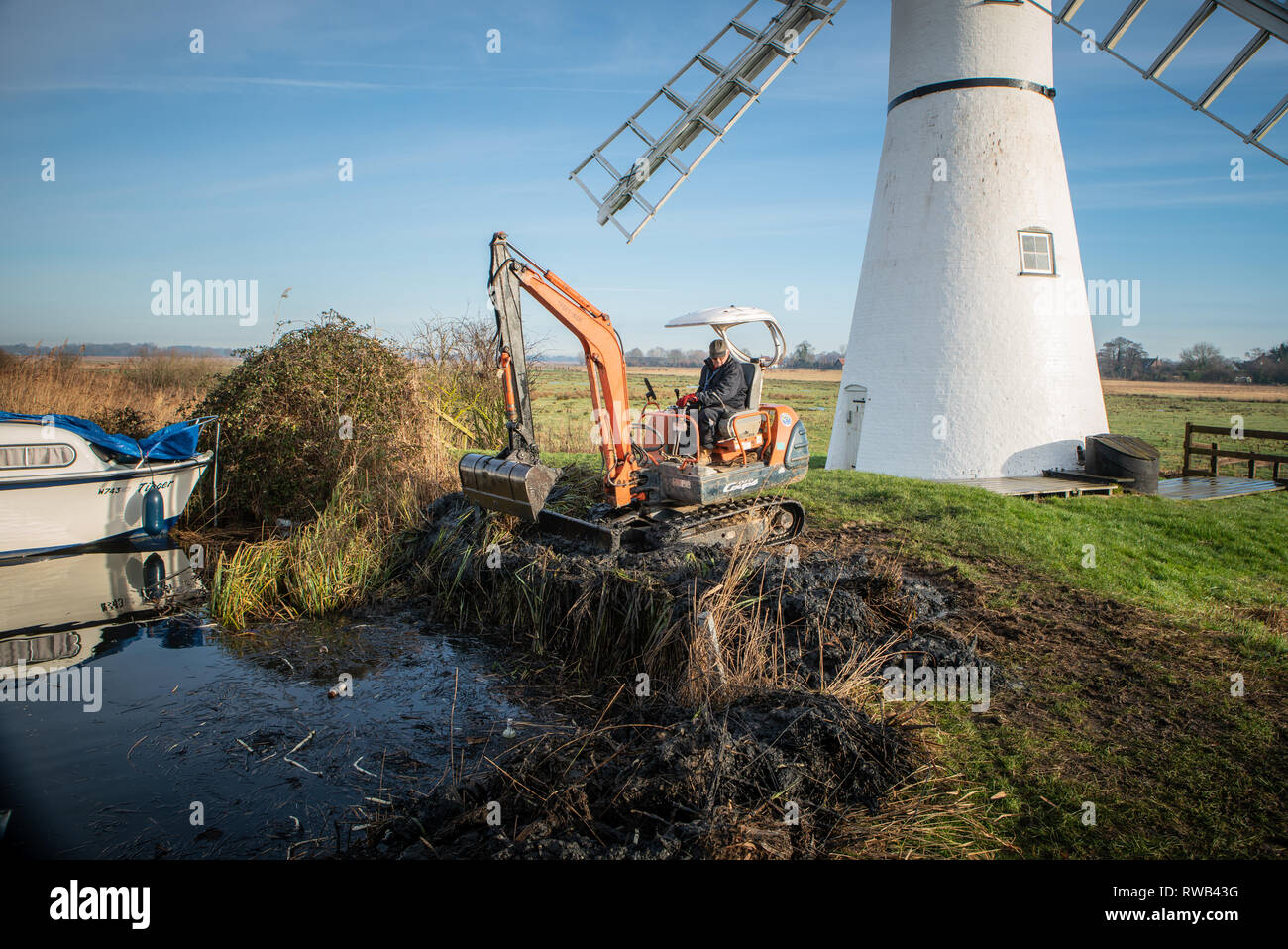 Workman, à l'aide d'un creuseur et godet pour draguer la rivière Thurne, sur le Norfolk​ Broads, UK Banque D'Images