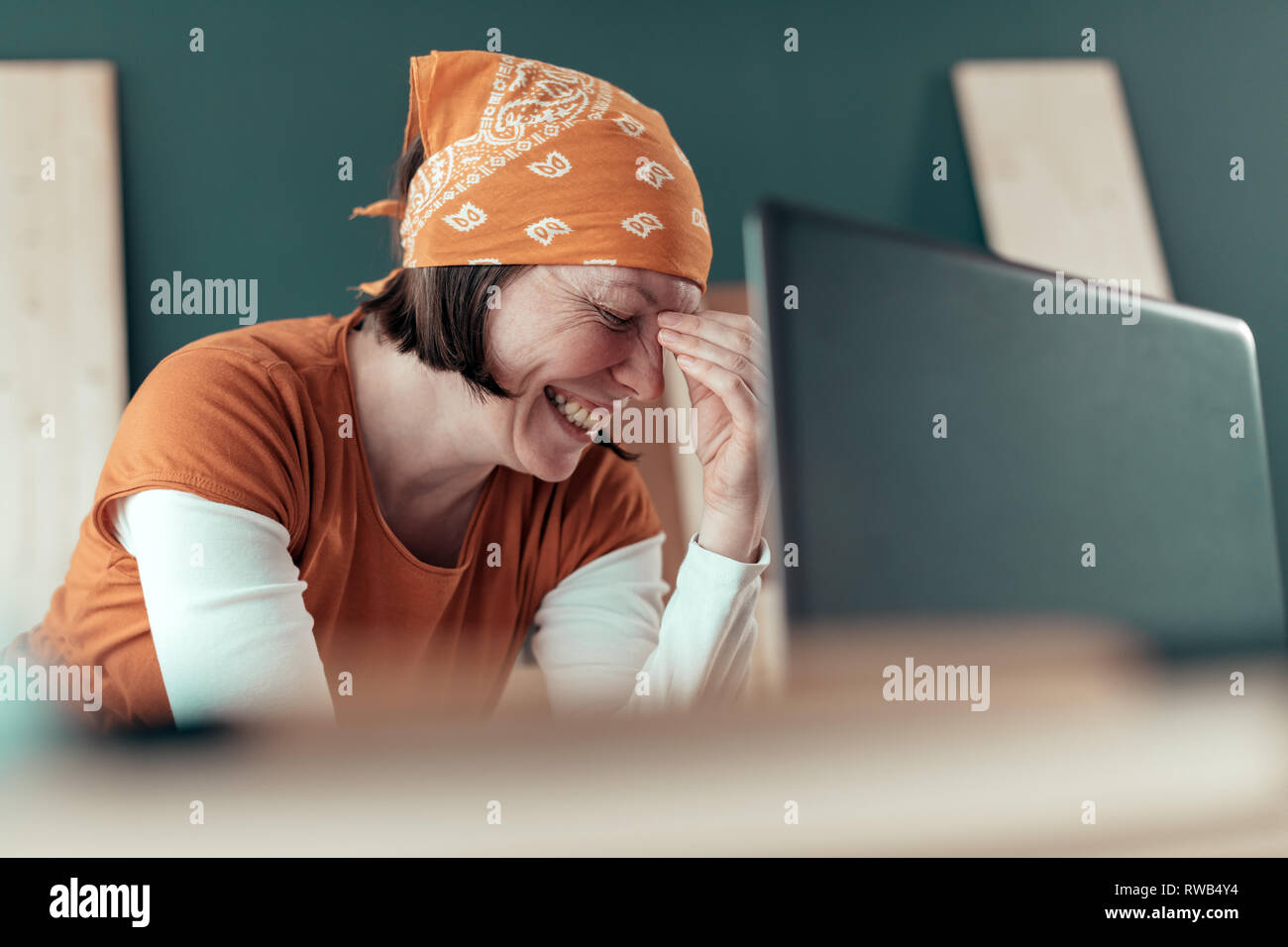 Happy smiling female carpenter lors de chat en ligne avec le client sur un ordinateur portable dans l'atelier de menuiserie Banque D'Images