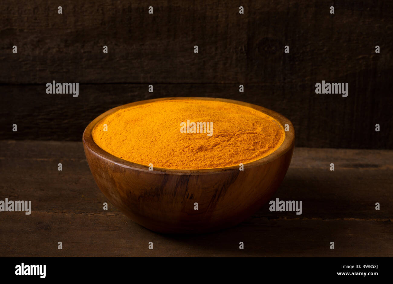 Le curcuma curcuma dans bol en bois et fond de bois, gros plan, vue avant Banque D'Images