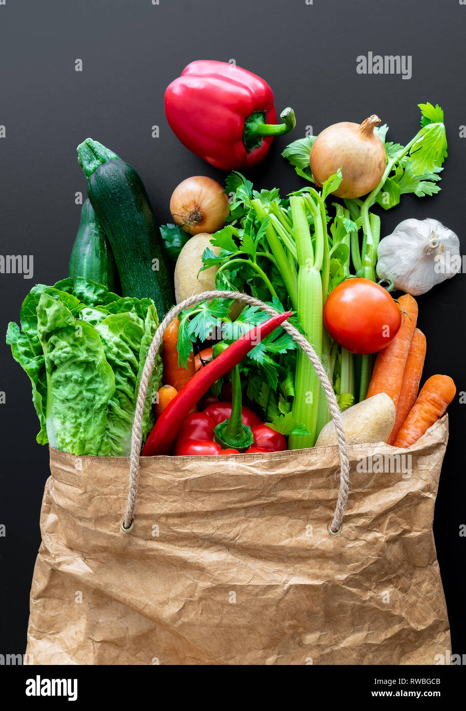 Les légumes frais biologiques en sac en papier brun contre l'arrière-plan du tableau sombre Banque D'Images