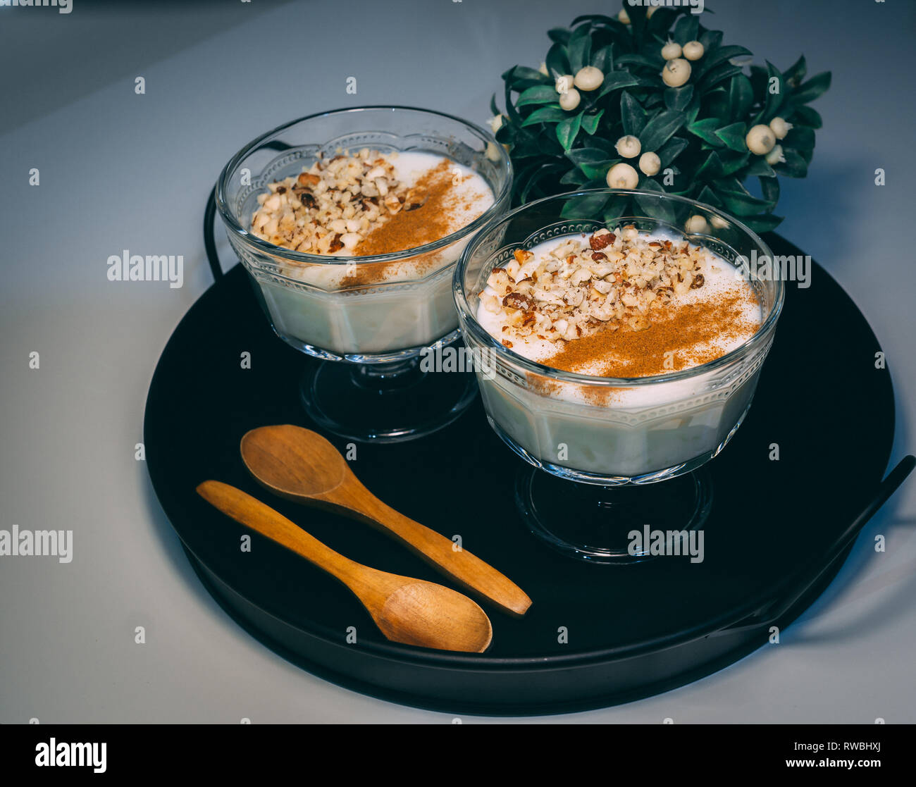 Riz au lait servi dans des tasses en verre. Décoré. Close-up.dessert Maison décorée avec des fleurs sur fond noir. Banque D'Images Riz au lait servi dans des tasses en verre. Décoré. Close-up.dessert Maison décorée avec des fleurs sur fond noir. Banque D'Images