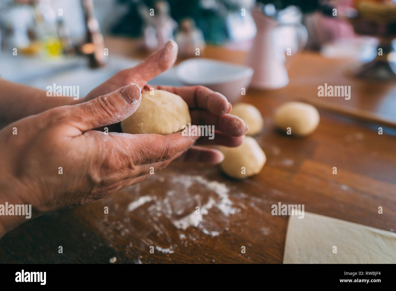 Mains d'une femme dans la cuisine façonner les boulettes. La formation de boules de pâte pour la cuisson sur la table en bois. Banque D'Images