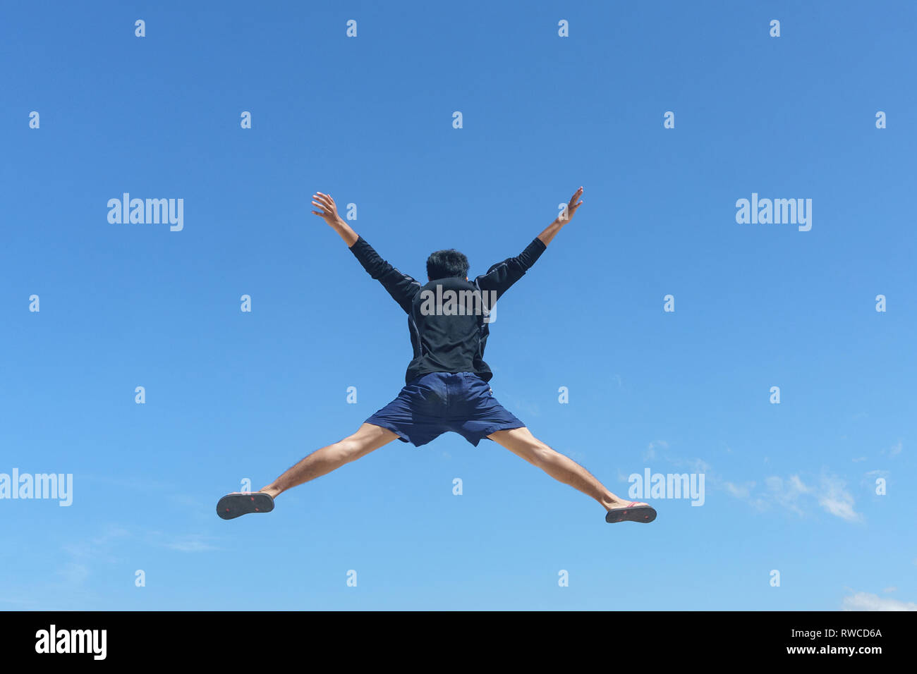 Jeune homme sautant contre ciel bleu paysage. Droit mou avec le jeune homme est en mouvement où certains effet flou sur sa jambe pour montrer le mouvement. Banque D'Images