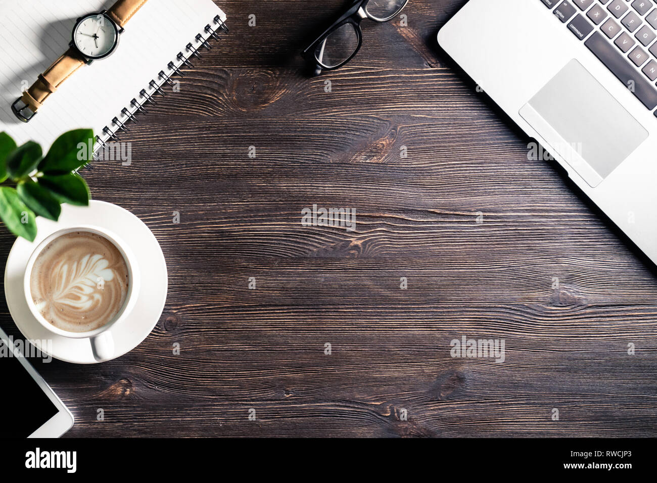 Bureau d'affaires avec ordinateur portable et téléphone portable lunettes stylo regarder sur table en bois foncé, fond de table de travail moderne avec des périphériques et du café Banque D'Images