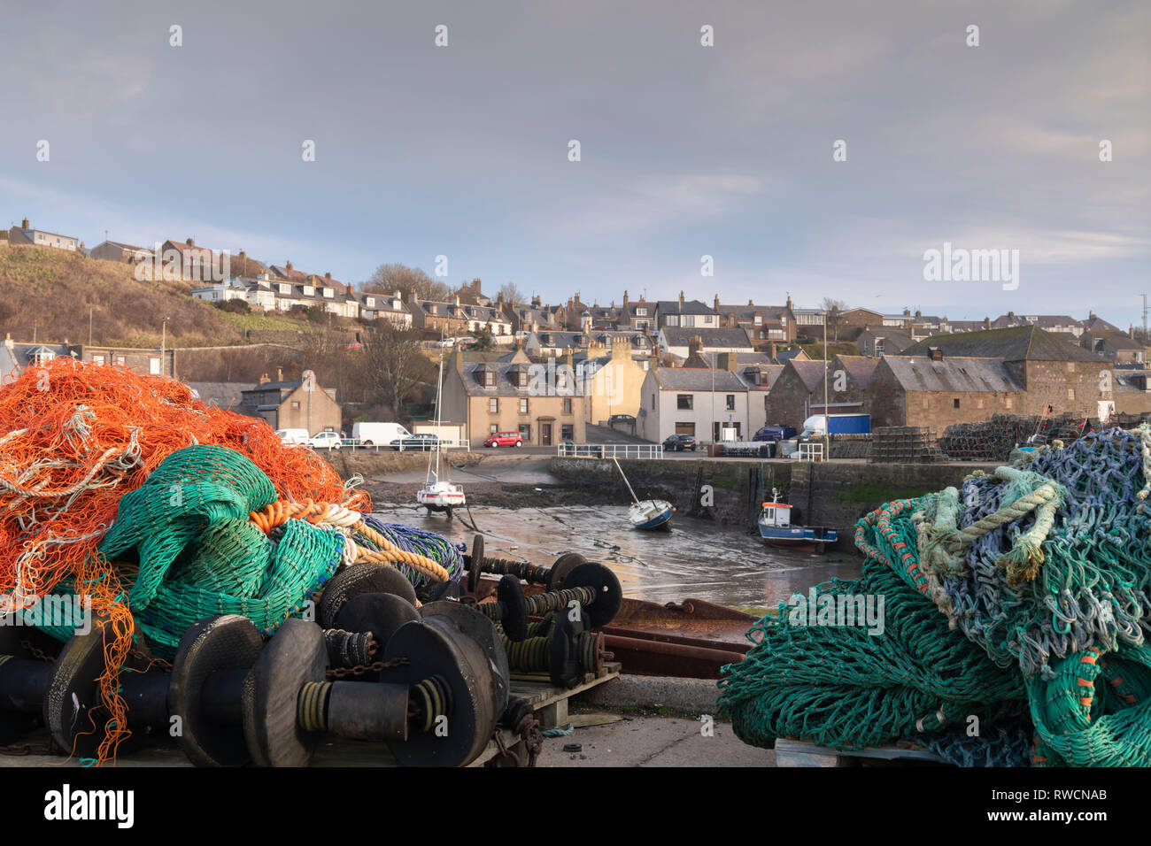 Filets colorés et d'autres équipements de pêche empilés sur le quai à Gourdon, un village sur la côte de l'Aberdeenshire Banque D'Images