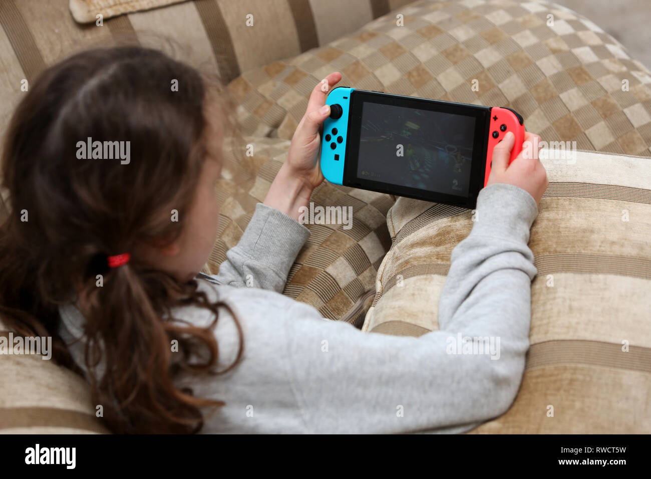 La photo d'une jeune fille jouant sur un commutateur de console de jeux Nintendo à son domicile à Londres, Royaume-Uni. Banque D'Images